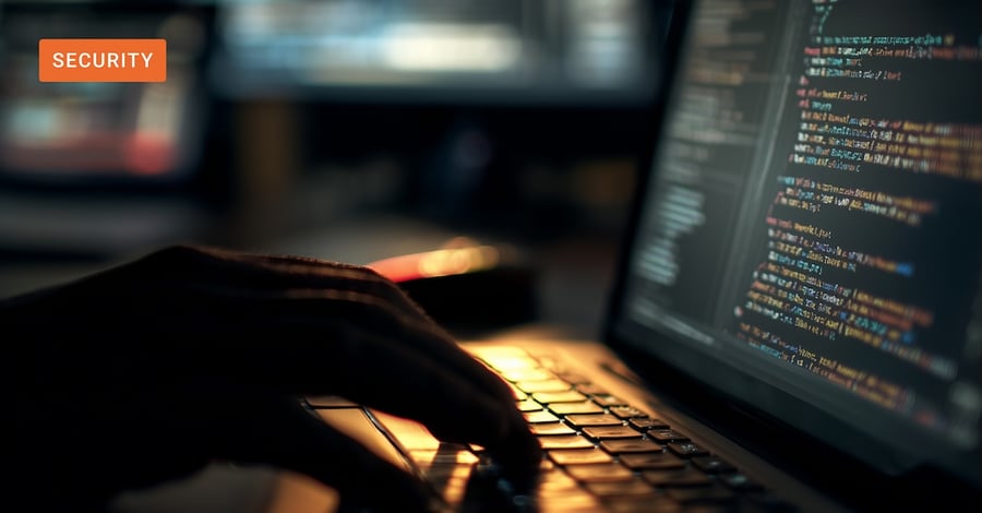 Hands typing on a backlit laptop keyboard at night with code on screen – AI agent security inside the enterprise.